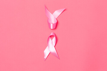 Women Healthcare Concept. Flat-lay Closeup Image of Two Small Pink Ribbons Against Coral Background as Symbol of Breast  Cancer Awareness During Cancer Fight  Campaign.