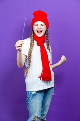 Portrait of One Expressive Caucasian Girl in Red Warm Hat and Red Scarf Having Fun With Vivid Bright Burning Bengal Light Fireworks Over Purple Background