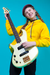 Winsome Caucasian Female Guitar Player With Yellow Bass Guitar Posing In Fashionable Yellow Hoody...