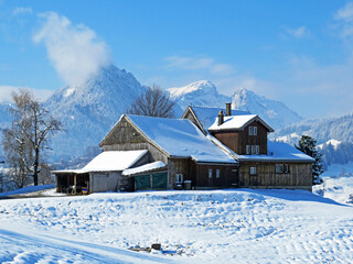 Indigenous alpine huts and wooden cattle stables on Swiss pastures covered with fresh white snow cover, Nesslau - Obertoggenburg, Switzerland (Schweiz)