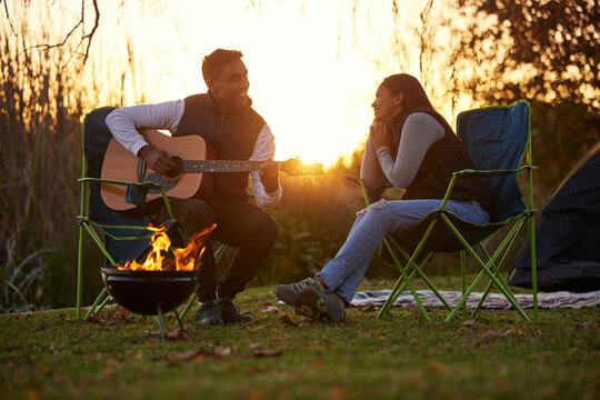 I wrote this for you. Shot of a young man serenading his girl while playing guitar during a camping trip.