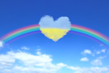 大きな虹とウクライナの国旗色のハート形の雲が浮かぶ青空