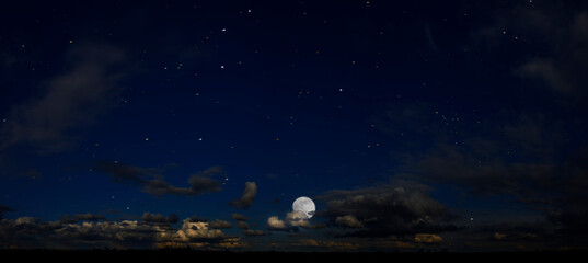 Fototapeta na wymiar Panorama of night sky with clouds and stars. Moonlight.