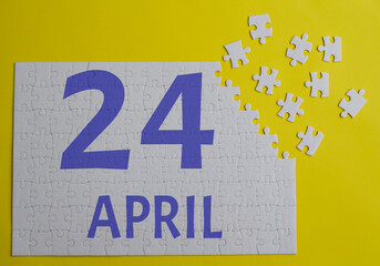 24 april calendar date on a white puzzle with separate details. Puzzle on a yellow background with a blue inscription