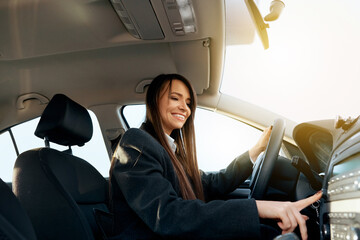 Young woman driving a car and adjusting car audio. Music in a car