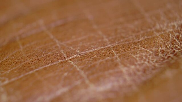 Wrinkled cracked brown natural leather surface. Macro. Dolly shot