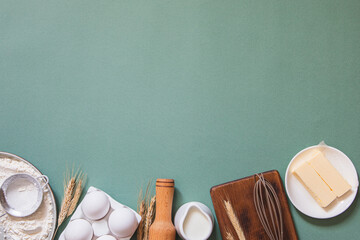 Frame of food ingredients for baking on a green pastel background. Cooking flat lay with copy...