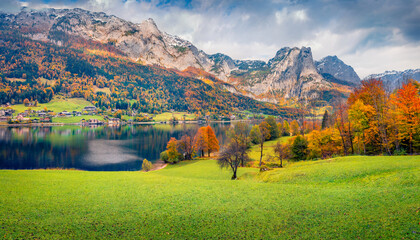 Dramatic autumn scenery. Colorful autumn view of Grundlsee lake with huge mountain range on...