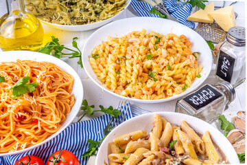 Set of pasta with different sauces on white tiled background. Spaghetti, farfalle, penne, fusilli pasta with seafood, spinach, carbonara, tomato sauce. Italian dinner, Mediterranean food concept