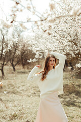 Obraz premium Young beautiful brunette woman in a blooming garden