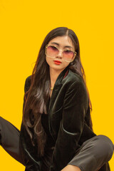 Fashion concept, Fashionable woman wear black outfits to sitting posing over yellow background
