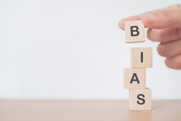 senior's hand arranged wooden cube blocks with the word Bias including copy space, prejudice....