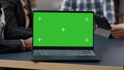 Laptop display with green screen background on office desk, people attending business meeting. Isolated mockup template with blank chroma key and copy space on computer screen. Close up. - Powered by Adobe