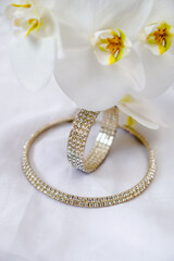 Bracelet and necklace on white fabric and white Orchid
