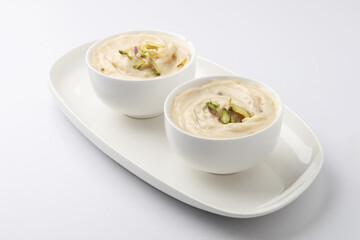 Shrikhand is an Indian sweet dish made of strained curd,garnished with dry fruits and saffron. Served in a ceramic bowl.Selective focus