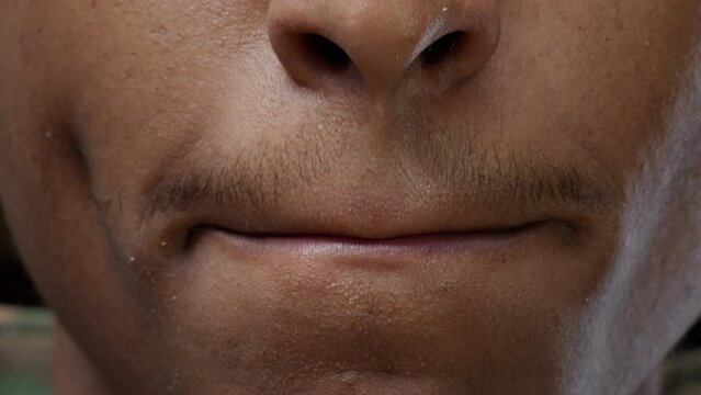 Macro shot of male model showing candid smile and moving lips, expressing positive emotions and smiling on camera. Happy man feeling confident about authentic facial expressions. Close up.