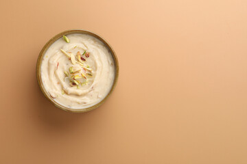 Shrikhand is an Indian sweet dish made of strained curd,garnished with dry fruits and saffron. Served in a ceramic bowl.Selective focus
