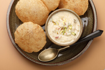 Shrikhand & Puri, Shrikhand is an Indian sweet dish made of strained curd,garnished with dry fruits and saffron. Served in a ceramic bowl & plate with Puri, Deep fried flat bread.Selective focus