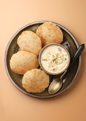Shrikhand & Puri, Shrikhand is an Indian sweet dish made of strained curd,garnished with dry fruits and saffron. Served in a ceramic bowl & plate with Puri, Deep fried flat bread.Selective focus