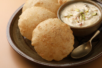 Shrikhand & Puri, Shrikhand is an Indian sweet dish made of strained curd,garnished with dry fruits and saffron. Served in a ceramic bowl & plate with Puri, Deep fried flat bread.Selective focus
