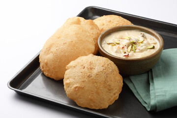 Shrikhand & Puri, Shrikhand is an Indian sweet dish made of strained curd,garnished with dry fruits and saffron. Served in a ceramic bowl & plate with Puri, Deep fried flat bread.Selective focus
