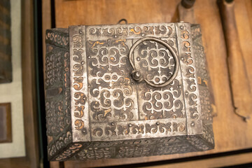 Historical metal chest or metal box with ring handle on wooden background, top view.