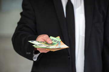 Young business man in a suit holding fan of euro banknotes