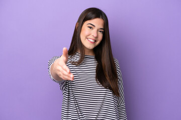 Young Brazilian woman isolated on purple background shaking hands for closing a good deal