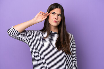 Young Brazilian woman isolated on purple background making the gesture of madness putting finger on...