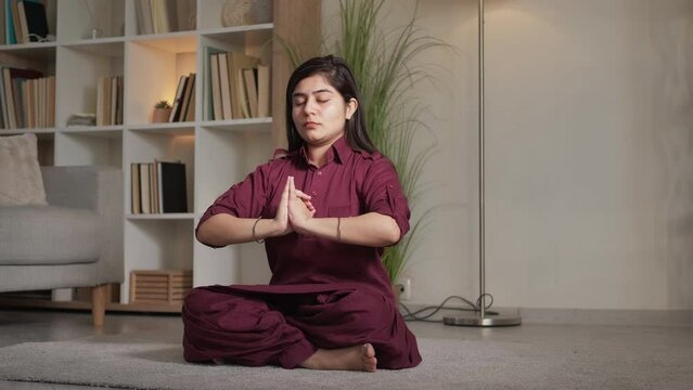 Meditation indoors. Yoga wellness. Spiritual practice. Peaceful mindful woman exercising mudra mahamayuri dhyana gestures in lotus position at home living room.
