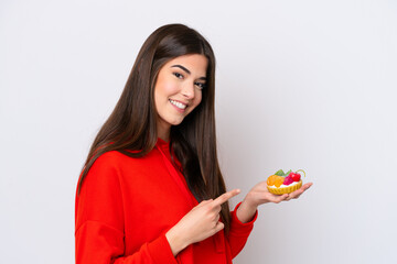 Young Brazilian woman holding a tartlet isolated on white background and pointing it