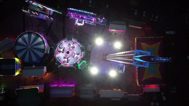 Aerial time lapse drone view fair showing several funfair attractions and wave swinger is amusement ride that is a variation on the carousel in which the seats are suspended from the rotating summit