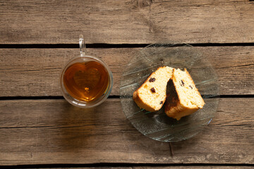 Mug with tea and homemade cake on a plate on the table at home for breakfast, cupcake and tea