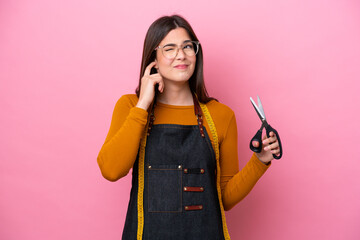 Young Brazilian seamstress woman isolated on pink background frustrated and covering ears