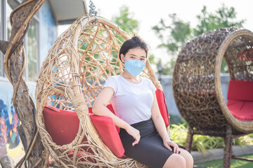 Fototapeta premium Asian girl wearing a mask detained and happy at home ,Stay home away from society, new normal behavior Coronavirus Covid-19 pm2.5. online education.