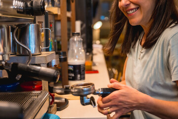 Smiling unrecognizable female cafeteria waitress preparing coffee in a coffee machine, covid restrictions are lifted and the mandatory use of face masks is removed