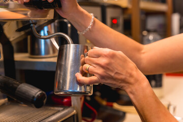 Unrecognizable female cafeteria waitress preparing coffee in a coffee machine