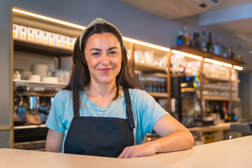 Portrait of a pretty smiling waitress with the coffee machine in the background, the covid...