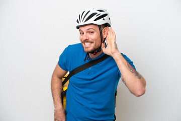 Young brazilian man with thermal backpack isolated on white background listening to something by putting hand on the ear