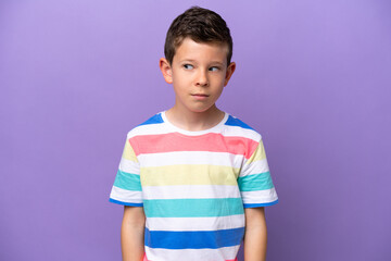 Little boy isolated on purple background making doubts gesture looking side