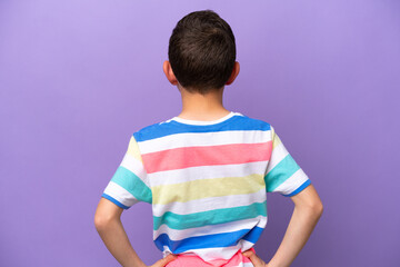 Little boy isolated on purple background in back position