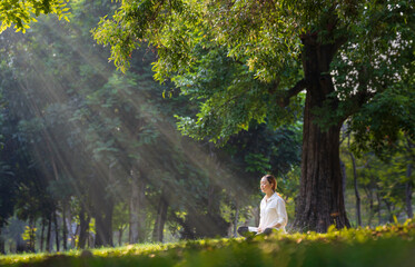 Woman relaxingly practicing meditation in the forest to attain happiness from inner peace wisdom...