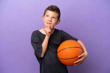 Little boy playing basketball isolated on purple background and looking up