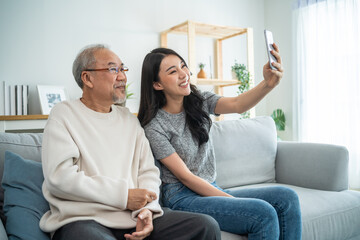 Fototapeta na wymiar Asian lovely family, young daughter use phone selfie with older father