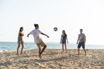 Group of Asian young man and woman play soccer on the beach together. 