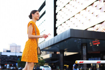 Fototapeta na wymiar Portrait fashion woman in yellow dress walking on street of the city, smiling to side