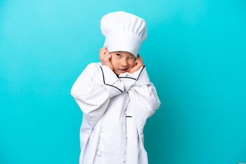 Little chef boy isolated on blue background frustrated and covering ears