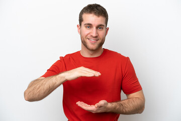 Young caucasian man isolated on white background holding copyspace imaginary on the palm to insert...