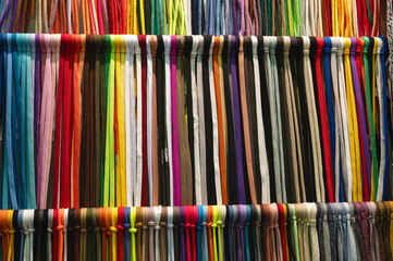 Collection of colorful lace samples hangs tied on rack bar