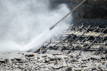 Obraz premium Worker cleaning corrosion damaged concrete bridge pillar with high pressure washer. Road bridge construction industry.